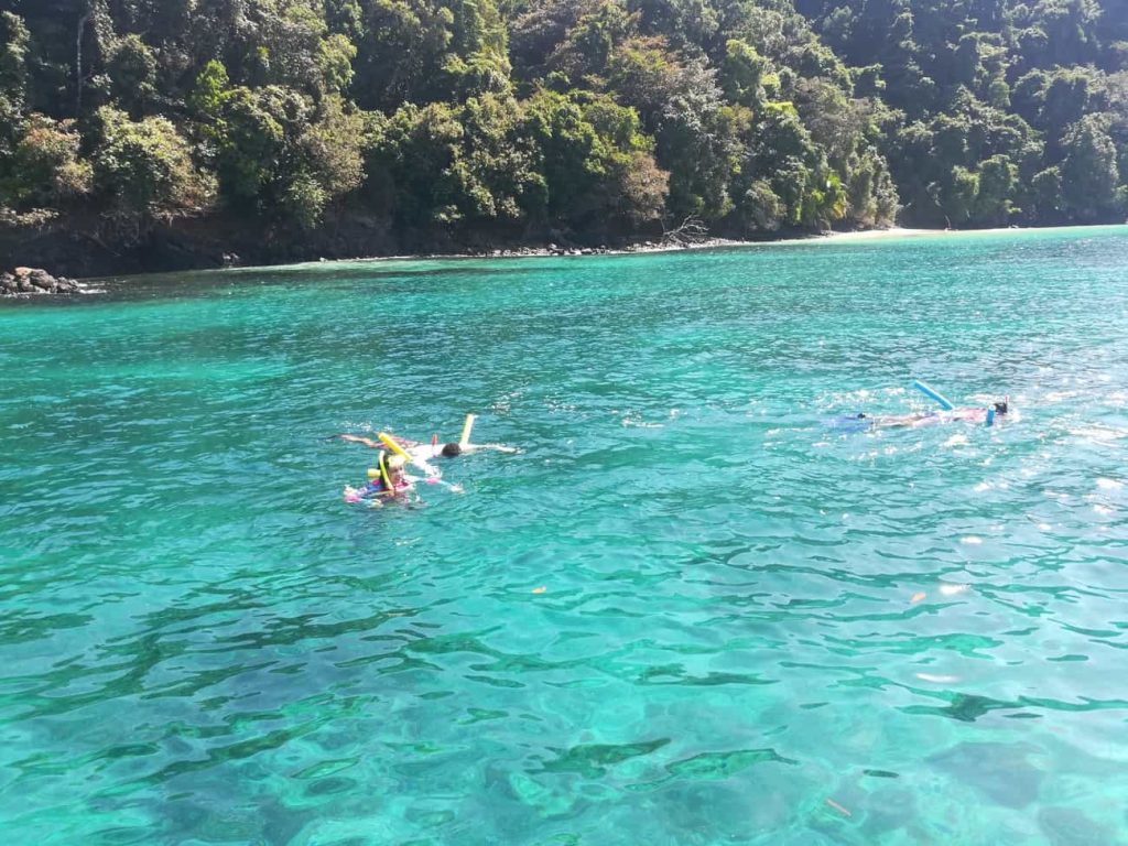 Personas haciendo snorkel en agua turquesa frente a una isla de selva en el Parque Nacional Coiba, Panamá